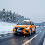 **A self-driving car navigating a snowy Swedish winter road. The car should be equipped with advanced sensors, and snow should be visible on the road and surrounding landscape. Focus on demonstrating the challenges of winter driving in Sweden.**